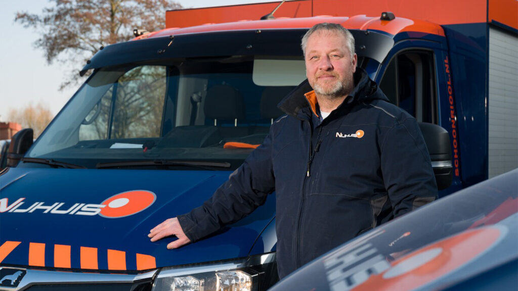 Medewerker van Nijhuis Rioolreiniging bij een bedrijfswagen in de herkenbare blauw-oranje huisstijl.
