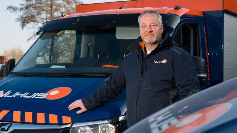 Medewerker van Nijhuis Rioolreiniging bij een bedrijfswagen in de herkenbare blauw-oranje huisstijl.