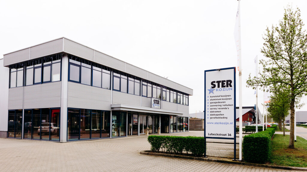 Bedrijfspand en showroom van Ster Kozijn in Oldenzaal met het bedrijfslogo en productoverzicht op het reclamebord.