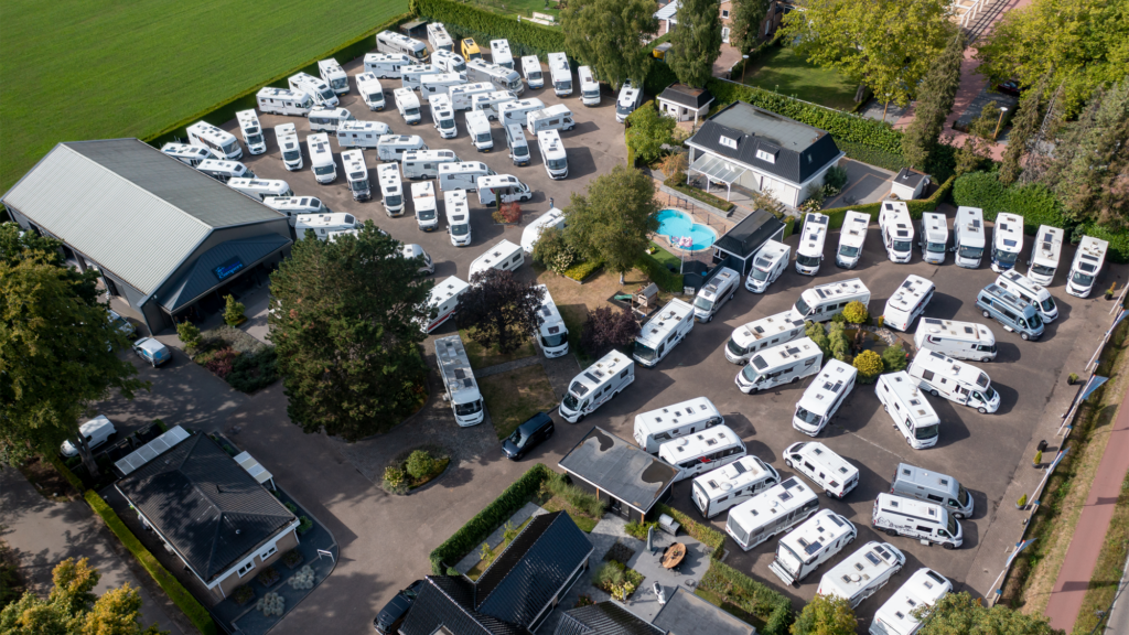 Luchtfoto van het terrein van Bakker Campers in Apeldoorn met tientallen campers en het bedrijfslogo.