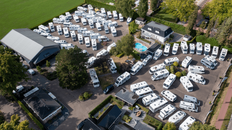 Luchtfoto van het terrein van Bakker Campers in Apeldoorn met tientallen campers en het bedrijfslogo.