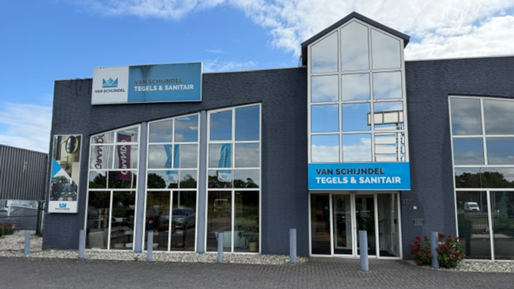 edrijfspand van Van Schijndel Tegels & Sanitair in Uden met de showroom en bedrijfsnaam op de gevel.